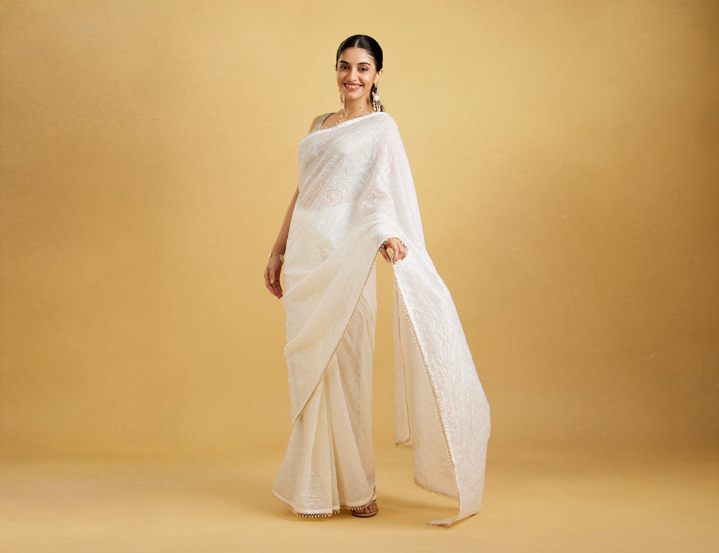 A lady posing in an embellished white saree